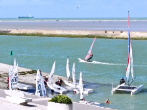 Vue panoramique depuis la chambre "côté embouchure" de Bouteille A la Mer® face à la mer et Gravelines : voiliers, windsurfers sur l'embouchure de l'AA, plage, et passage de bateaux en mer du Nord, Côte d'Opale.