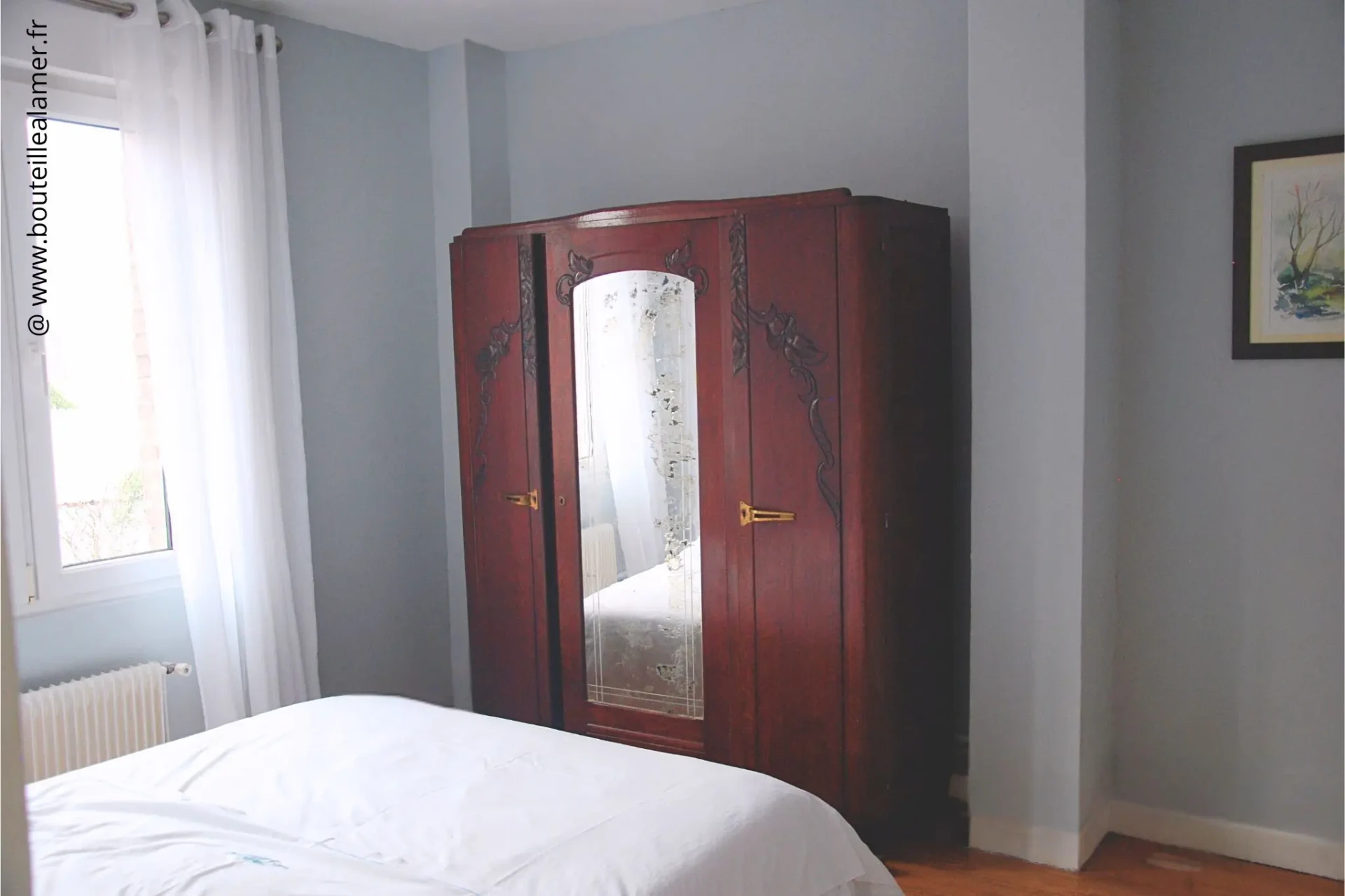 Chambre double lumineuse avec armoire ancienne à miroir, vue jardin côté Club de voile, gîte Bouteille à la Mer sur la Côte d’Opale à Gravelines, location maison de vacances.