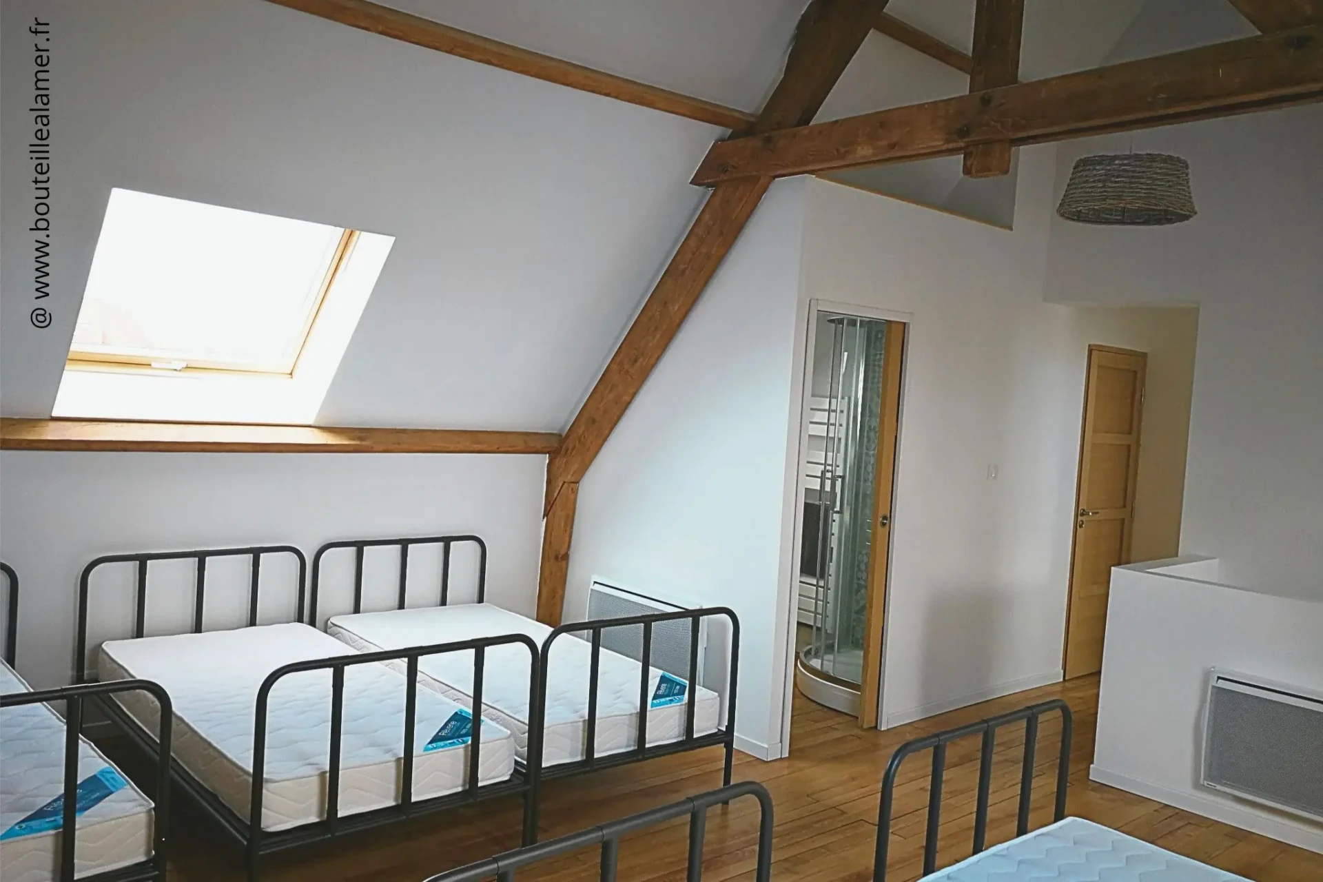 Dortoir lumineux avec cinq lits simples, poutres apparentes, parquet, salle de bain privative et toilettes à l’étage, gîte Bouteille à la Mer, Côte d’Opale, Gravelines.